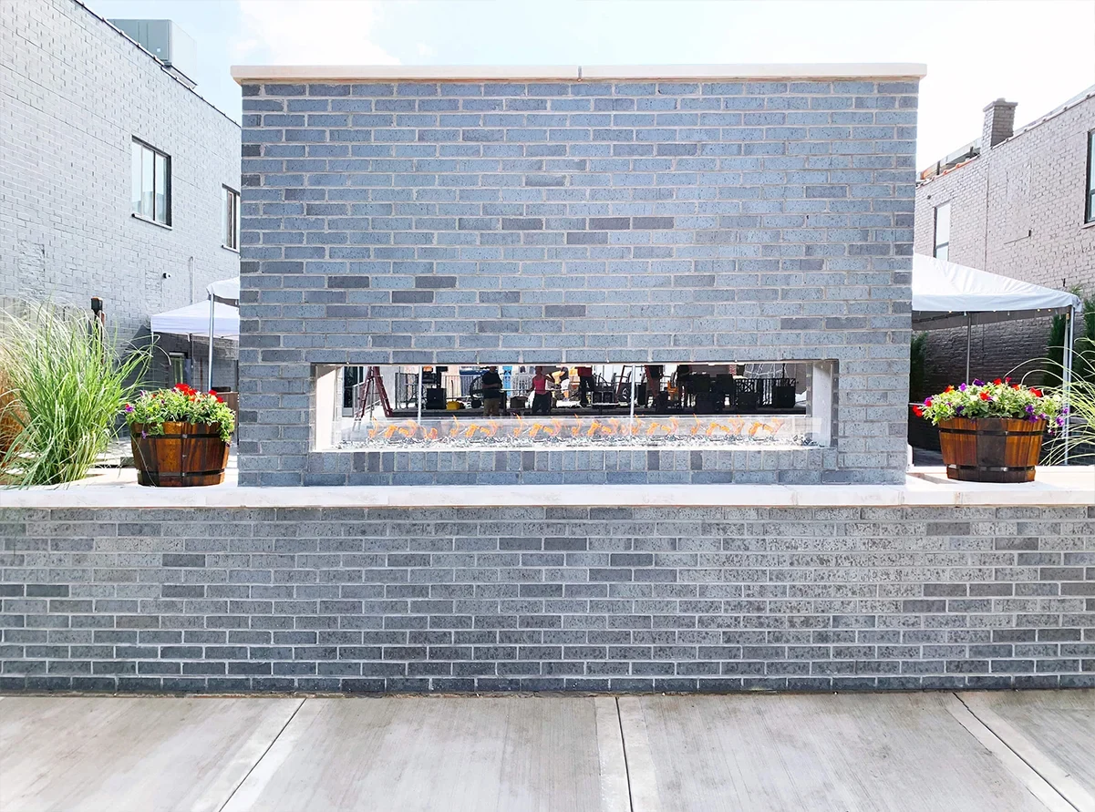 Flare VST-100 outdoor see-through linear gas fireplace set into a brick wall