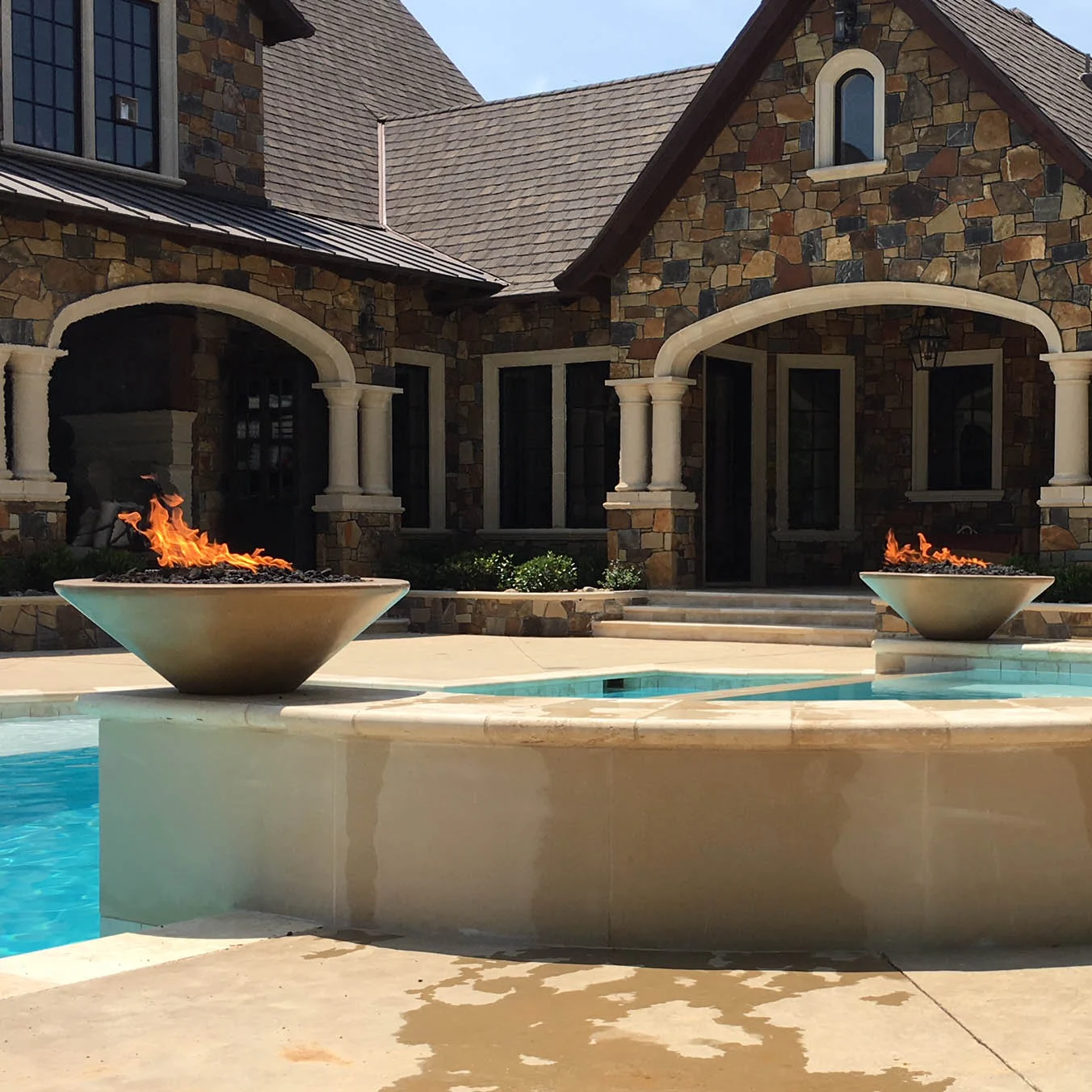 The Outdoor Plus Cazo fire bowls installed beside a pool